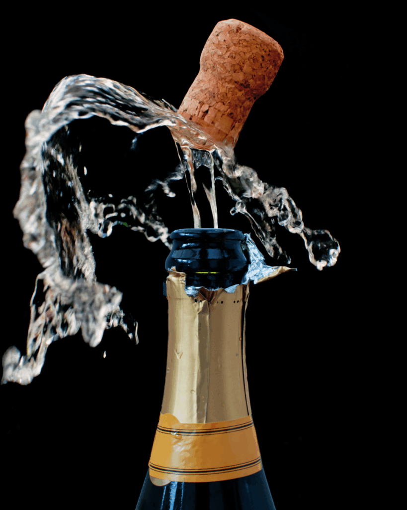 Шампанское. Пробка вылетает из горлышка бутылки вместе с брызгами шампанского