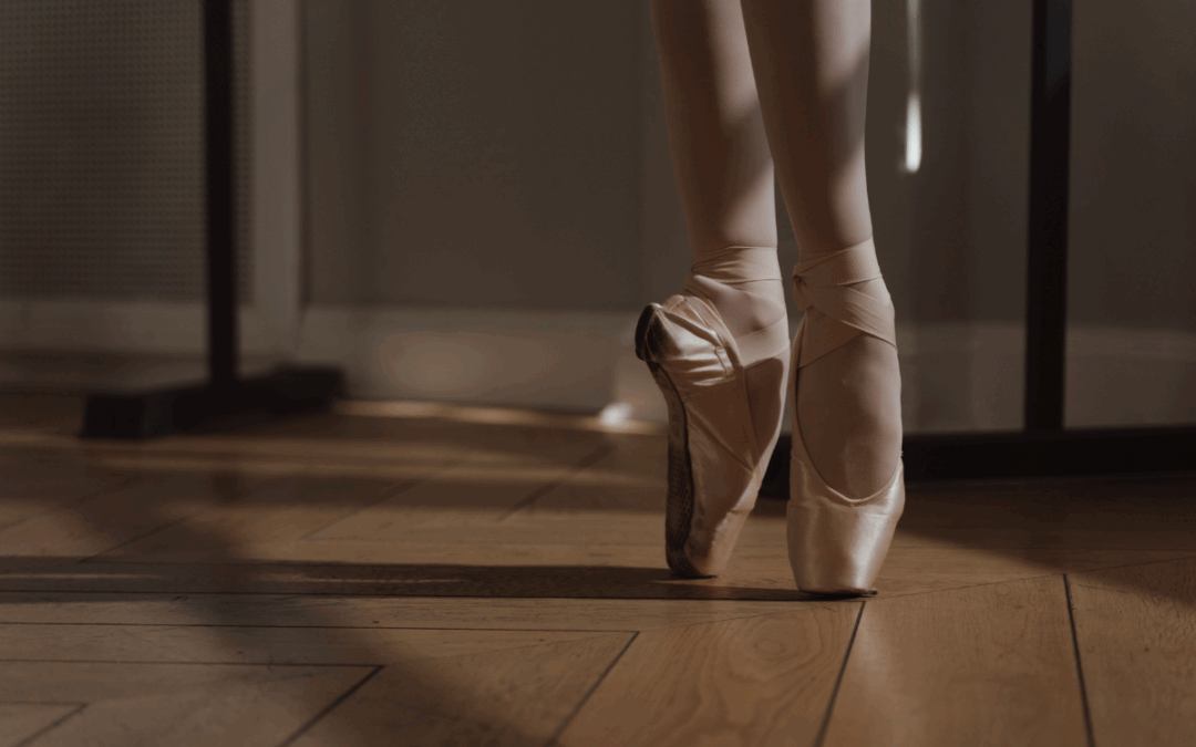 Две женские ноги в пуантах стоят на цыпочках, символизируя балет и изящество танца.