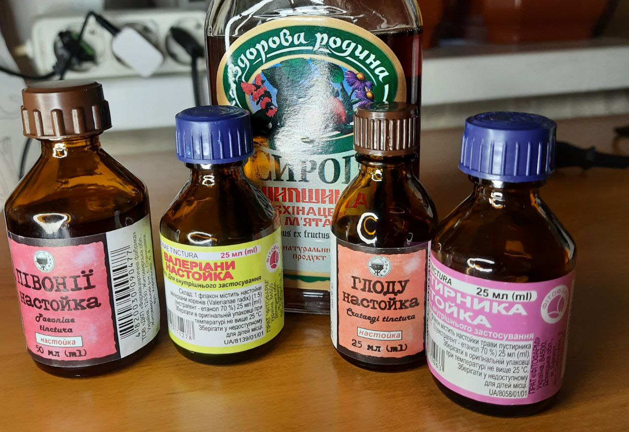 Набор небольших пузырьков с настойками на деревянной поверхности. Этикетки успокоительного, но один из них явно сияет как герой.